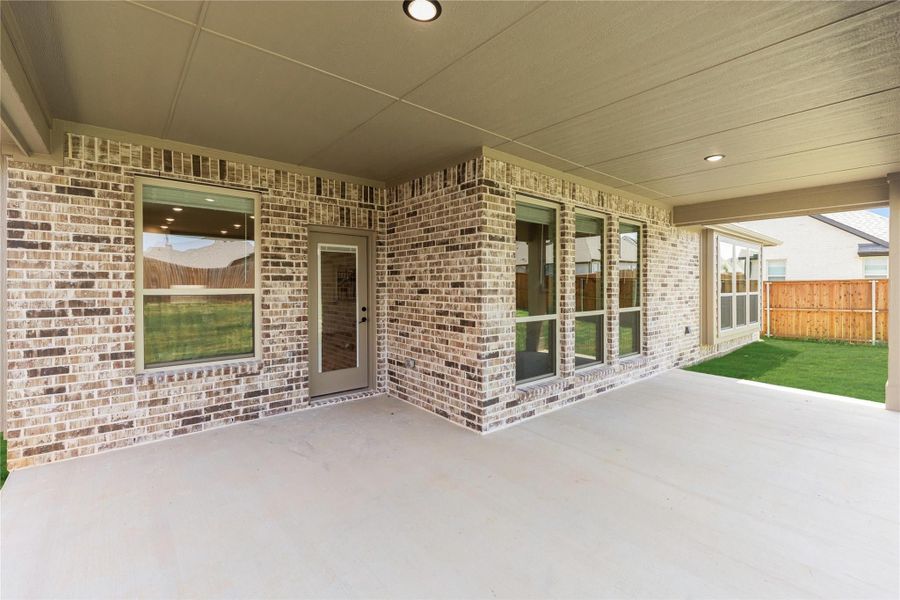 Covered concrete patio with brick exterior wall, multiple windows, and fenced backyard Covered concrete patio with brick exterior wall, multiple windows, and fenced backyard