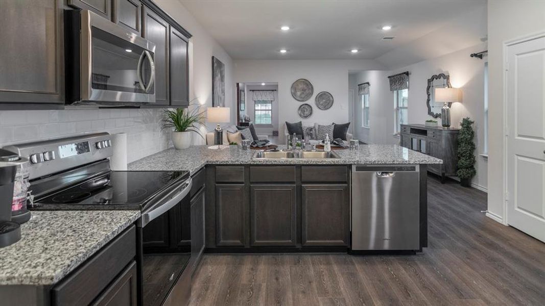 Kitchen featuring stainless steel appliances, a peninsula, light stone counters, open floor plan, and recessed lighting