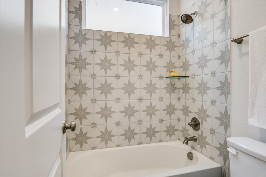 Bathroom featuring a tub and shower combination with star-patterned tile surround