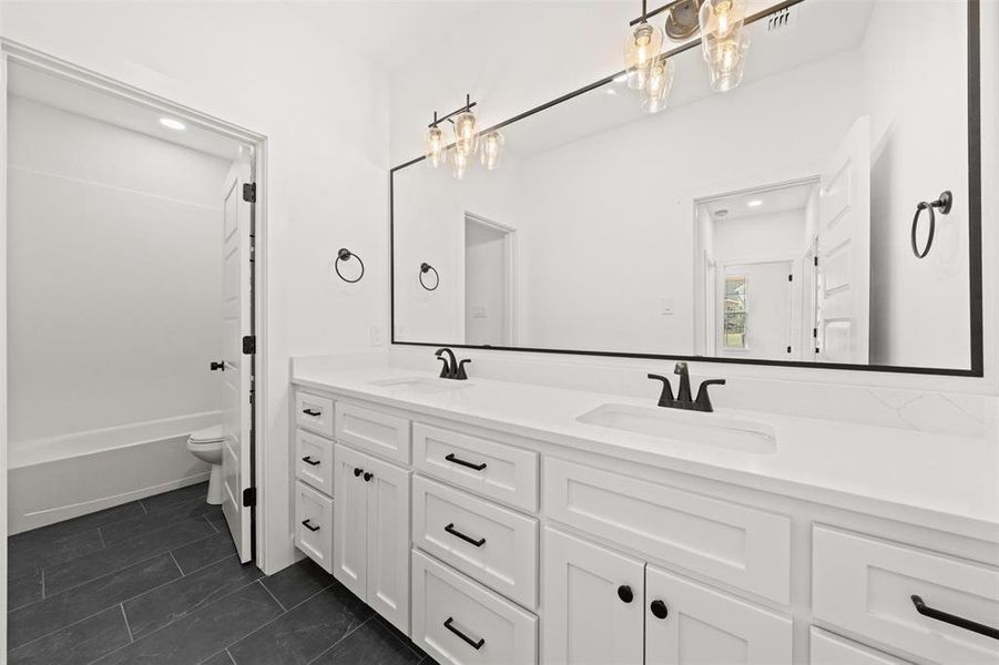Full bath featuring double vanity and dark tile patterned floors