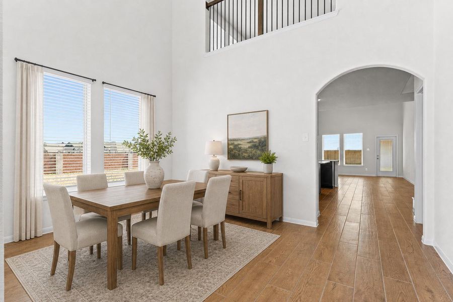Spacious interior view highlighting the beautiful wood looking tile flooring that extends through the first floor living areas, creating a seamless and stylish look. Natural light fills the space through large windows while the elegant arched opening leads toward the heart of the home. *Photo is Virtually Staged*