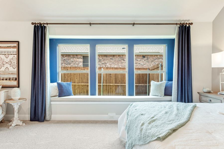 Bedroom with built-in window seat, three windows, blue accent wall, and navy curtains