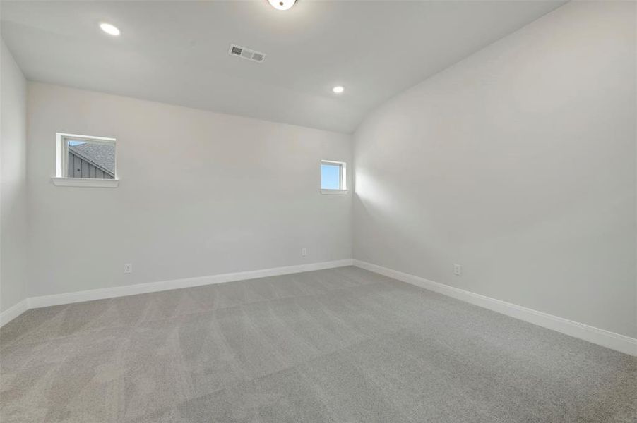 Spare room featuring light colored carpet, lofted ceiling, and recessed lighting