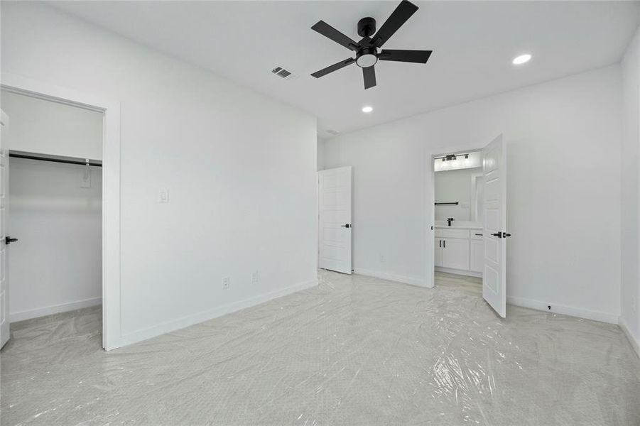 Unfurnished bedroom featuring recessed lighting, a walk in closet, ensuite bathroom, a ceiling fan, and a closet Unfurnished bedroom featuring recessed lighting, a walk in closet, ensuite bathroom, a ceiling fan, and a closet