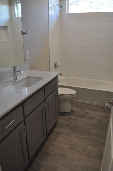 Full bathroom with vanity, tiled shower / bath combo, wood-type flooring, and toilet