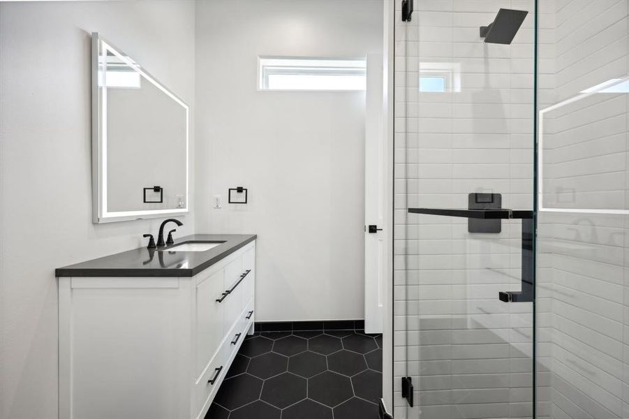 Bathroom with vanity, walk in shower, and tile patterned flooring