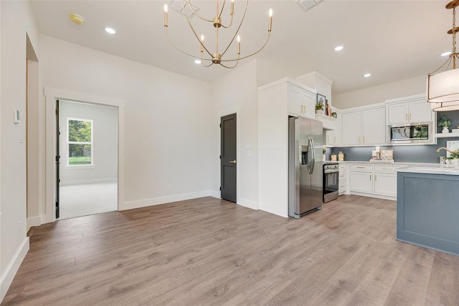 Kitchen with open shelves, white cabinets, stainless steel appliances, light wood-type flooring, and recessed lighting