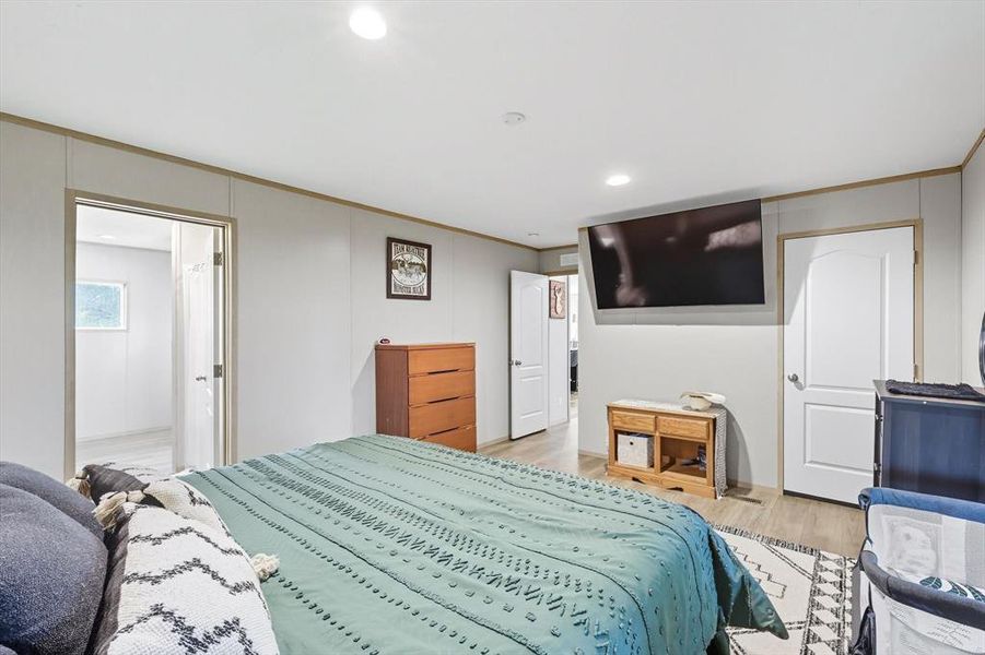 Bedroom with crown molding, light wood-style flooring, and recessed lighting Bedroom with crown molding, light wood-style flooring, and recessed lighting