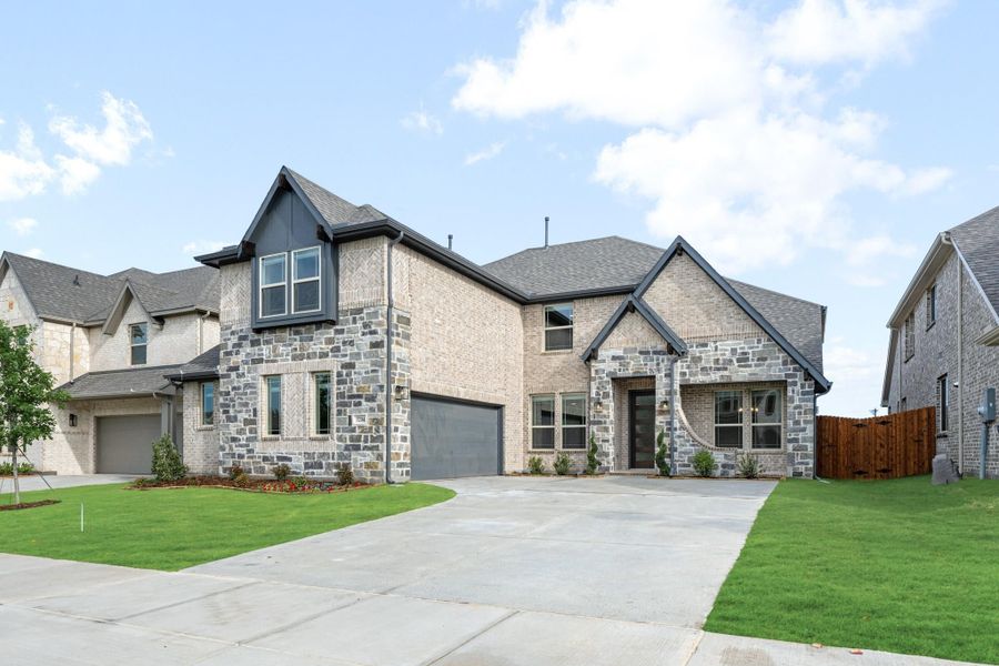 Two-story home with brick and stone exterior, two-car garage, and green front lawn Two-story home with brick and stone exterior, two-car garage, and green front lawn