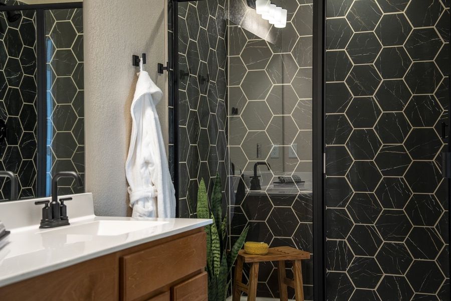 Walk-in shower with hexagon tile surround and matte black enclosure at primary bath