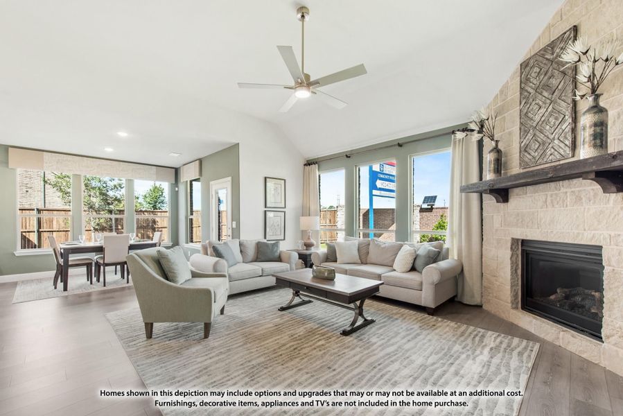 Open living room with vaulted ceiling, stone fireplace, ceiling fan, and dining area in background Open living room with vaulted ceiling, stone fireplace, ceiling fan, and dining area in background