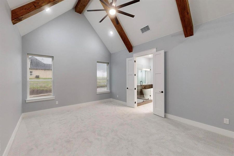 Unfurnished bedroom featuring beamed ceiling, ensuite bath, and light carpet