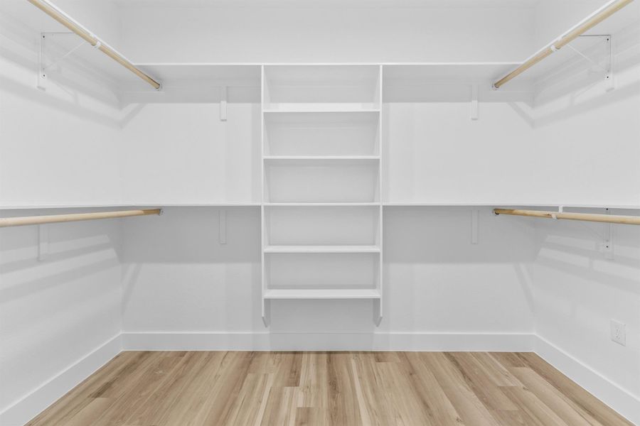 Spacious primary closet featuring light wood-style flooring