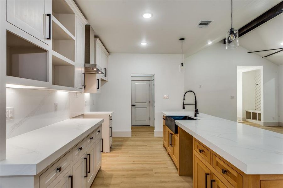 Kitchen featuring light wood-style floors, wall chimney range hood, recessed lighting, white cabinets, and an island with sink Kitchen featuring light wood-style floors, wall chimney range hood, recessed lighting, white cabinets, and an island with sink