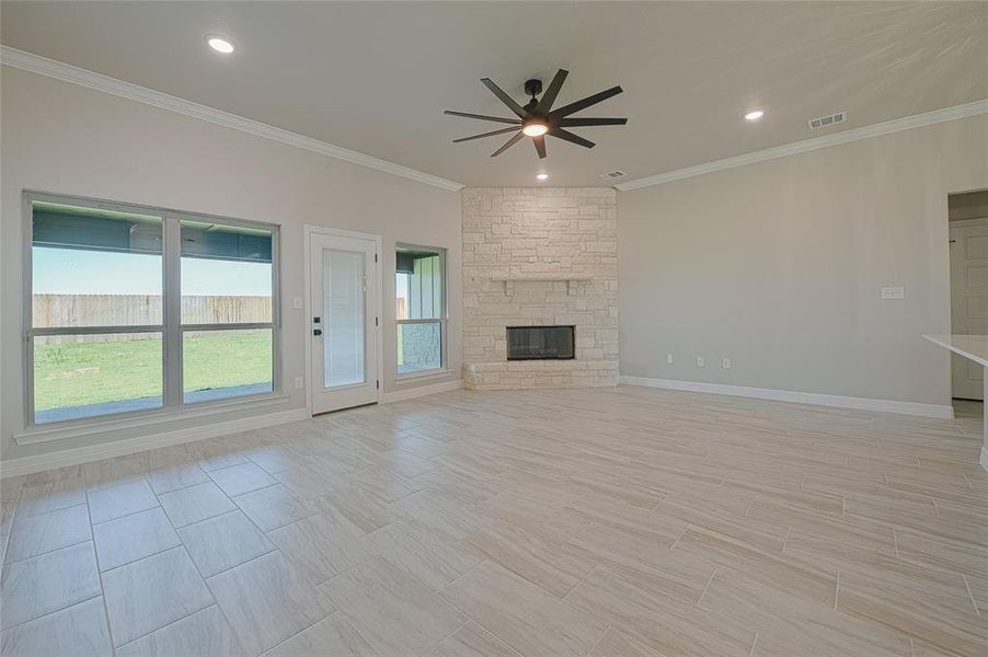 Unfurnished living room featuring ornamental molding, a stone fireplace, recessed lighting, ceiling fan, and wood tiled floors