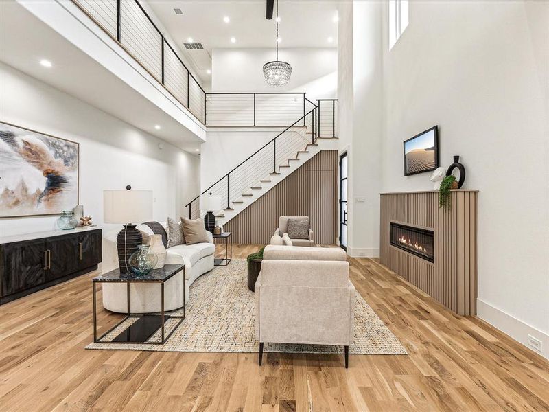 Living room with a notable chandelier, light hardwood / wood-style flooring, and a high ceiling