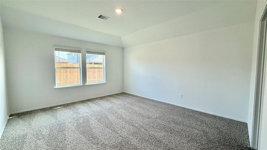 Spacious primary bedroom filled with natural light and overlooking the backyard.