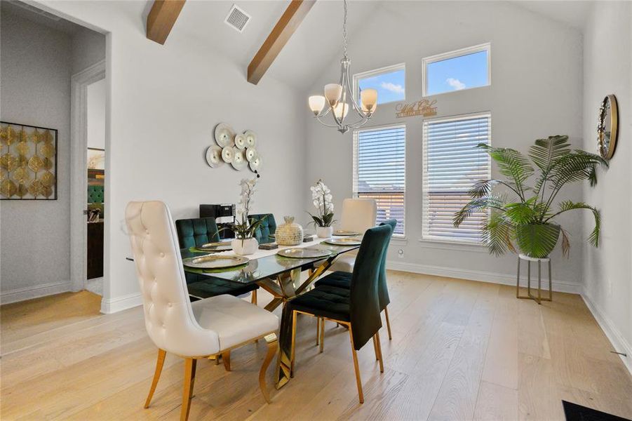 Dining area with high vaulted ceiling, light wood finished floors, a chandelier, and beam ceiling Dining area with high vaulted ceiling, light wood finished floors, a chandelier, and beam ceiling
