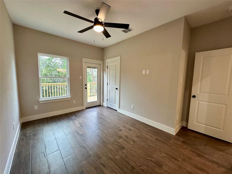 Unfurnished bedroom featuring access to exterior, dark wood finished floors, and a ceiling fan