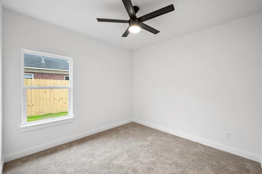 Carpeted spare room with ceiling fan and baseboards