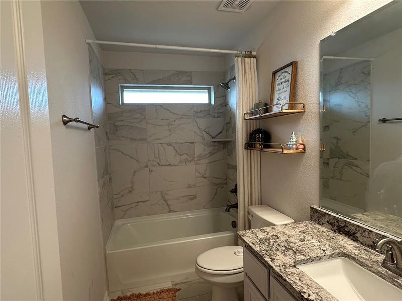 Ensuite Bathroom with shower / tub combo with curtain, vanity, and a textured wall