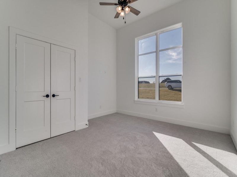 Unfurnished bedroom featuring light colored carpet, a ceiling fan, and a closet