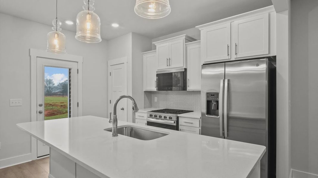 Highly skilled kitchen design includes a 9-foot island, quartz countertops, and stylish pendant fixtures