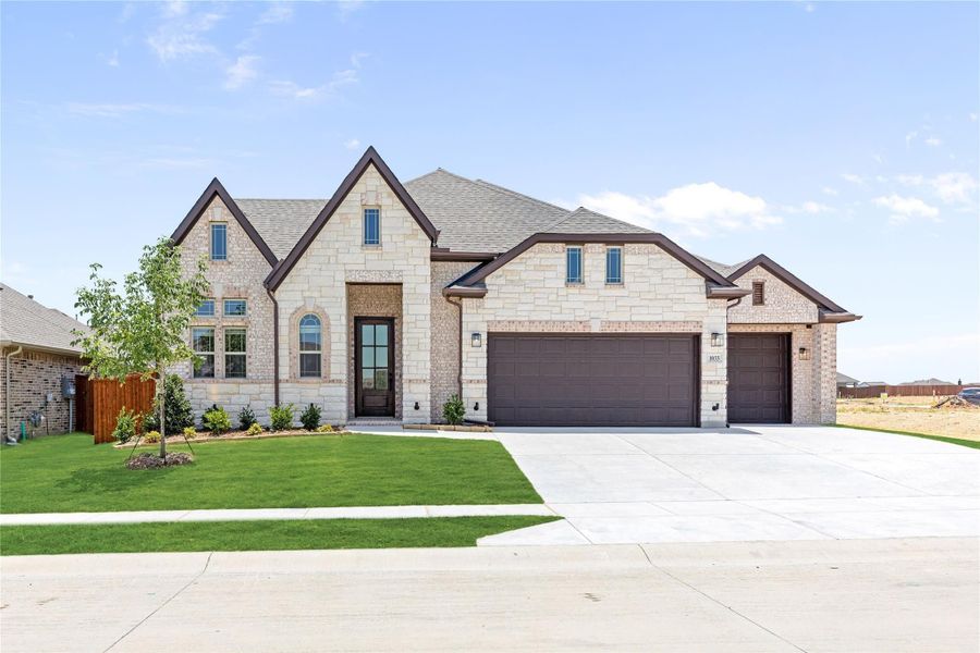 Two-story home with cream stone exterior, three-car garage, and manicured front lawn Two-story home with cream stone exterior, three-car garage, and manicured front lawn