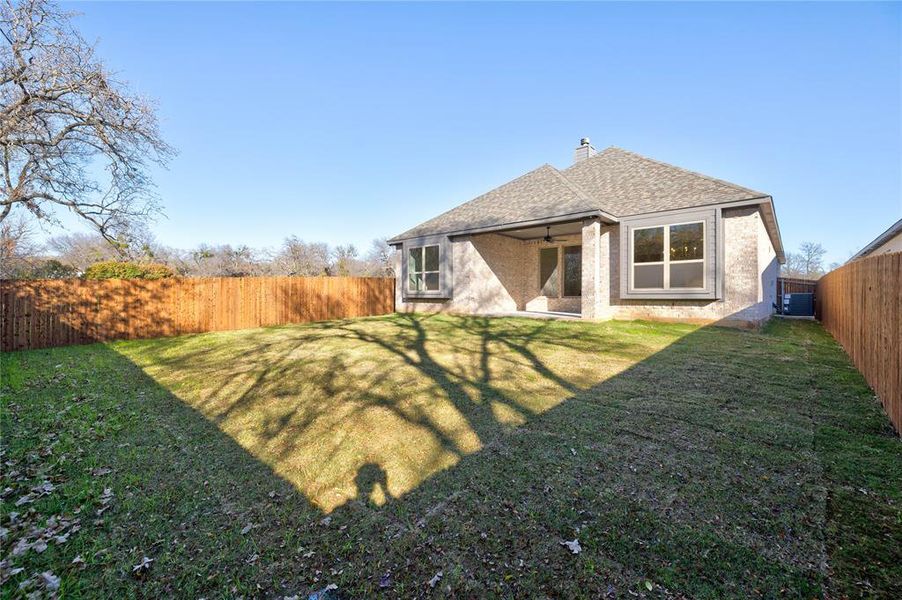 Back of house featuring a lawn, ceiling fan, and central AC