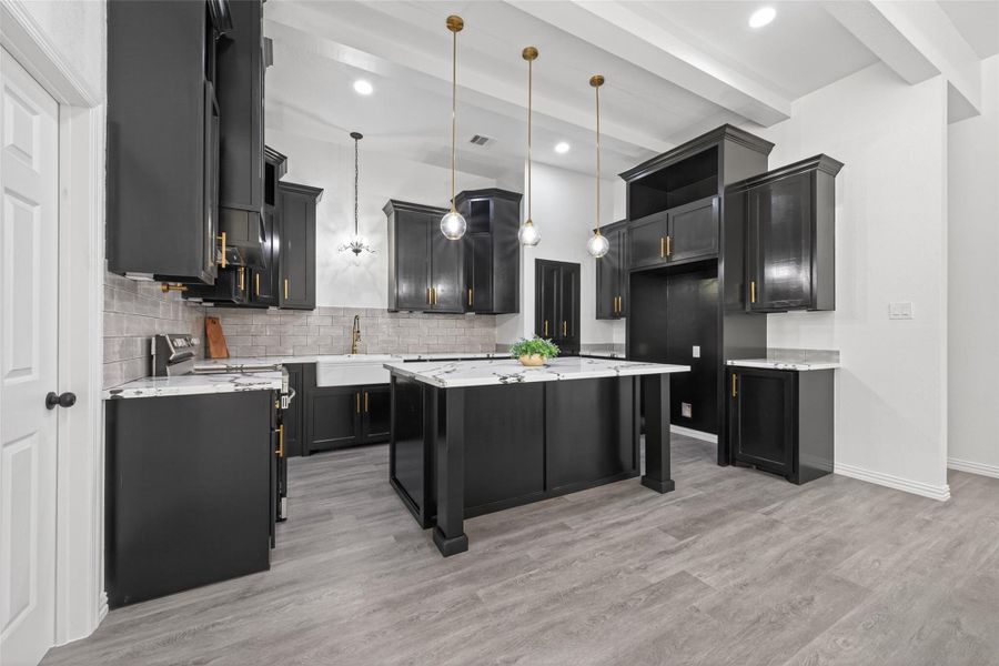 Stunning chef’s kitchen with oversized island, abundant custom cabinetry, modern finishes, and ample prep space for everyday living.