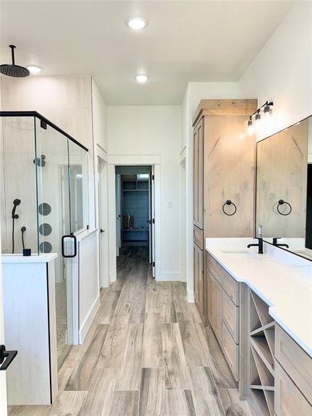 Bathroom with recessed lighting, wood finished floors, vanity, baseboards, and a stall shower