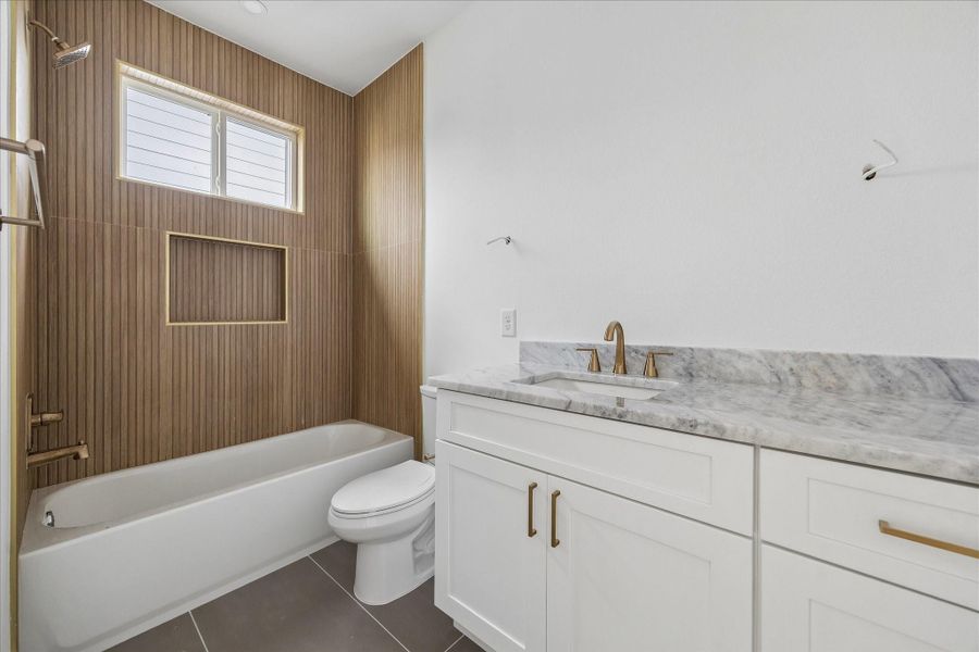 Ensuite bath for the third bedroom features dolomite countertops, wood-look tile, and a shower/tub combo.