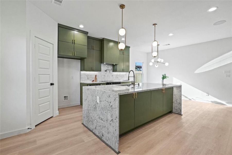 Kitchen featuring green cabinets, backsplash, decorative light fixtures, light wood-style floors, and a chandelier
