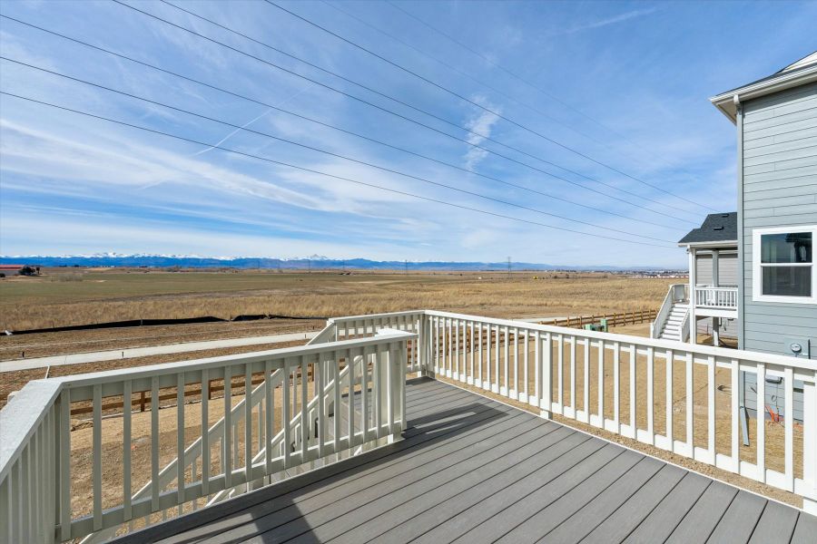 A wooden deck with a building and a field in the background. A wooden deck with a building and a field in the background.