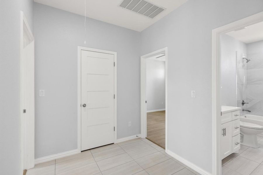 Hall featuring light tile patterned floors and baseboards Hall featuring light tile patterned floors and baseboards