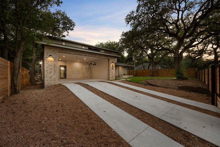 Contemporary house featuring a fenced backyard, brick siding, and driveway