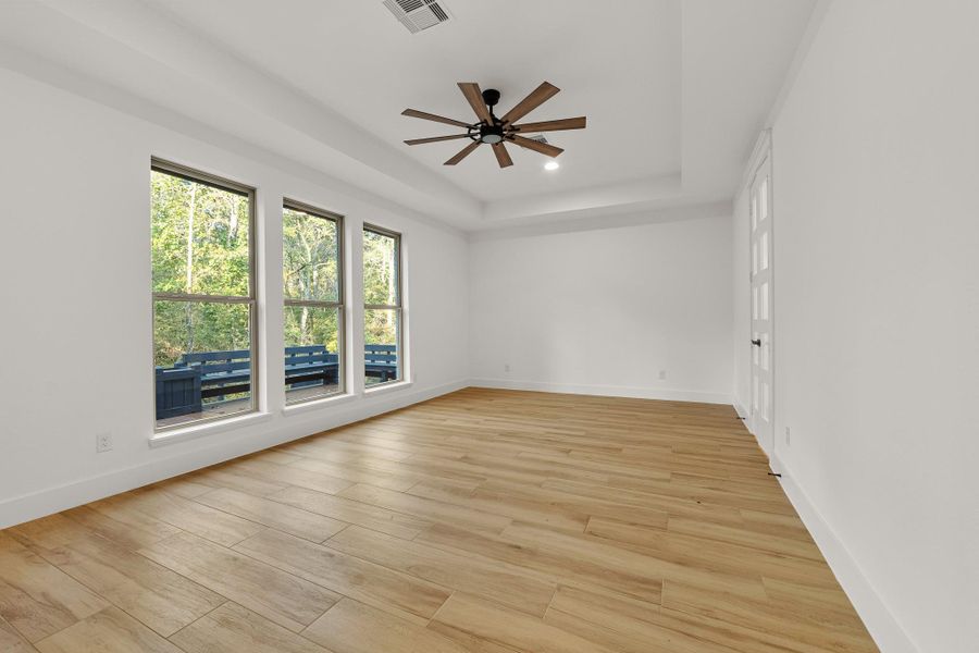 Bright, spacious primary room with large windows offering natural light and wooded views. Features sleek tile flooring, a ceiling fan, and a modern, airy feel. Bright, spacious primary room with large windows offering natural light and wooded views. Features sleek tile flooring, a ceiling fan, and a modern, airy feel.