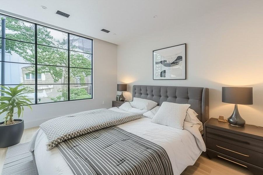 An inviting bedroom features a large, gridded window framing a verdant outdoor view. AI Staging