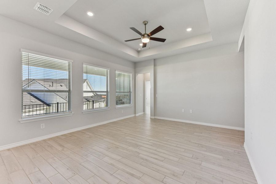 Unfurnished room with a raised ceiling, light wood-style flooring, ceiling fan, and recessed lighting Unfurnished room with a raised ceiling, light wood-style flooring, ceiling fan, and recessed lighting