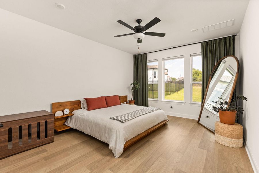 Bright interior space featuring wood-finish flooring, a contemporary ceiling fan, and three large windows