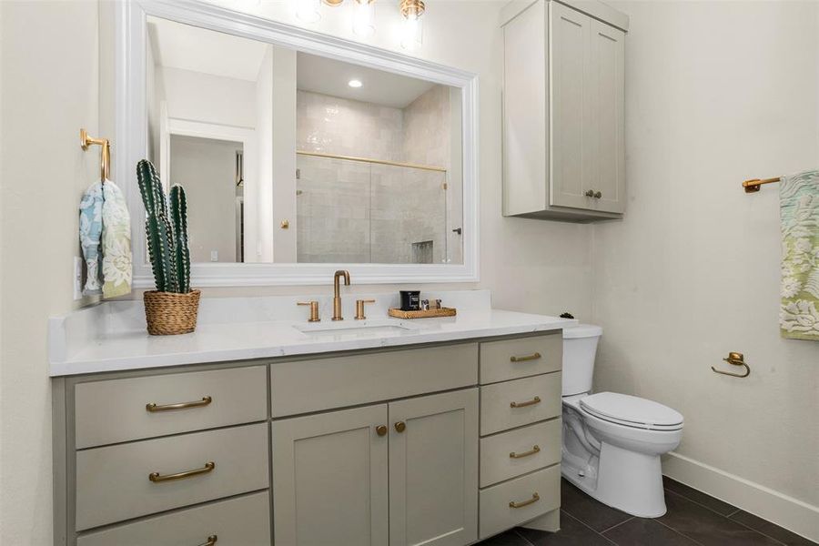 Full bath featuring vanity, a tile shower, and dark tile patterned floors Full bath featuring vanity, a tile shower, and dark tile patterned floors