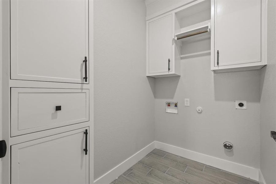 Washroom featuring hookup for an electric dryer, gas dryer hookup, baseboards, cabinet space, and hookup for a washing machine