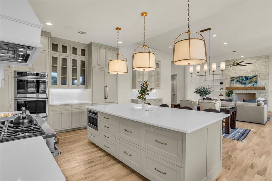 Kitchen with pendant lighting, custom exhaust hood, open floor plan, a ceiling fan, and recessed lighting Kitchen with pendant lighting, custom exhaust hood, open floor plan, a ceiling fan, and recessed lighting