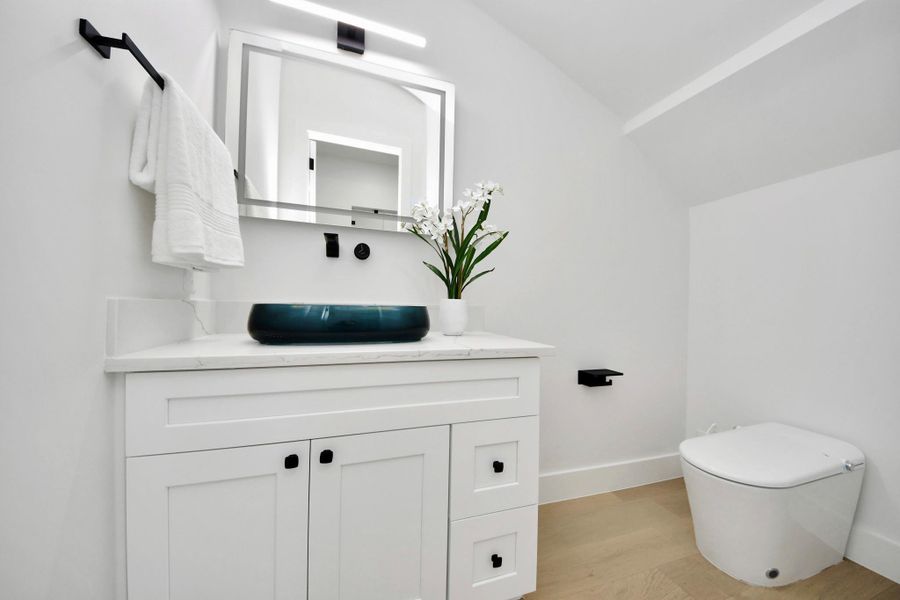 The half bathroom showcases a chic over-the-counter sink, paired with an LED mirror for a sophisticated and modern statement.