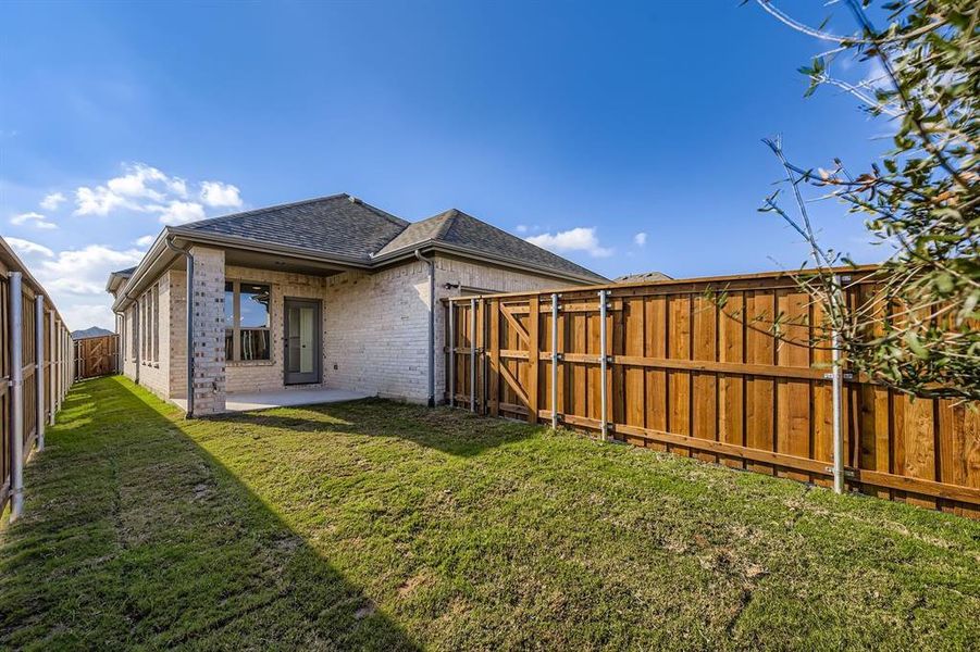 Back of house featuring a fenced backyard, a shingled roof, a patio, brick siding, and a gate Back of house featuring a fenced backyard, a shingled roof, a patio, brick siding, and a gate