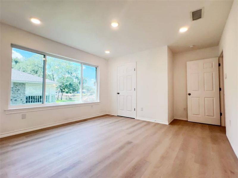 Expansive window framing exterior views, complemented by wood-finish flooring, recessed lighting, and crisp white walls