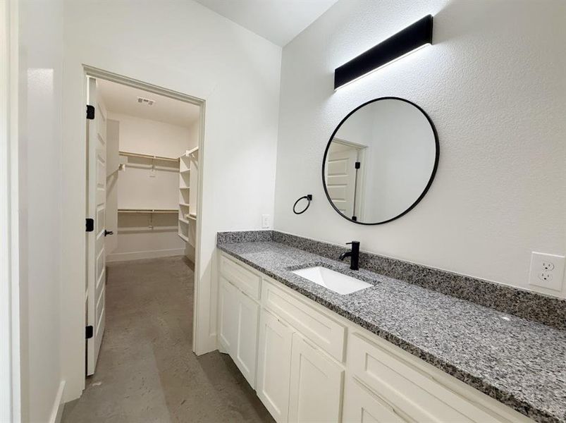 Bathroom with concrete floors, vanity, and a spacious closet Bathroom with concrete floors, vanity, and a spacious closet