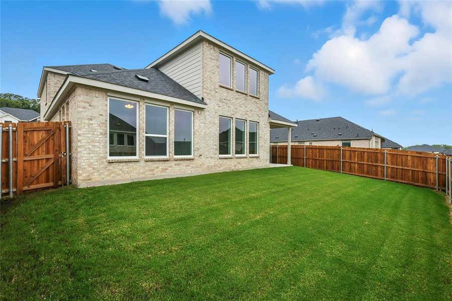 Back of house with brick siding, a fenced backyard, roof with shingles, and a gate Back of house with brick siding, a fenced backyard, roof with shingles, and a gate