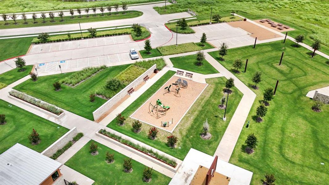 Central community playground featuring multiple play structures, a sandy ground cover, and surrounding benches Central community playground featuring multiple play structures, a sandy ground cover, and surrounding benches