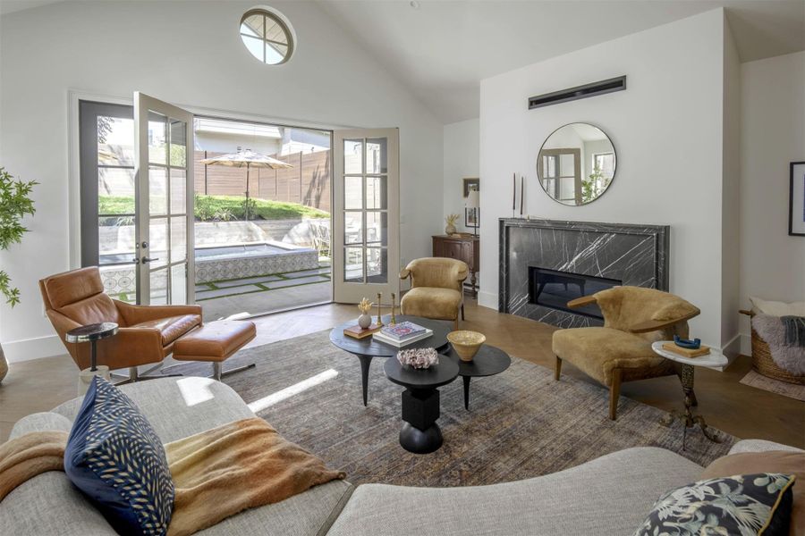 A striking black marble fireplace anchors the living space under vaulted ceilings and French doors. A striking black marble fireplace anchors the living space under vaulted ceilings and French doors.
